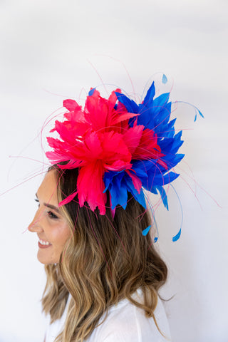 Woman wearing a colorful headpiece with pink and blue feathers on a white background
