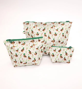 Three fabric zippered pouches in different sizes with a repeating duck print on a white background and green zipper pulls, photographed on a clean white background.