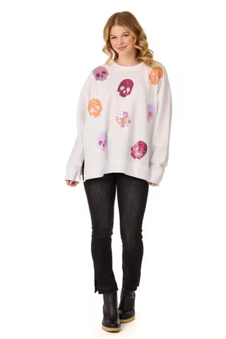 Woman wearing a white sweater with colorful skull designs on a white background