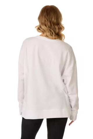 A woman viewed from the back wearing a loose white long-sleeve crewneck sweatshirt and black pants, set against a plain white background.