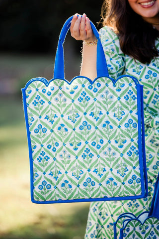 Person holding a green and blue patterned tote bag outdoors
