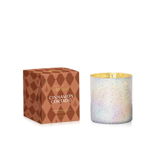 Candle with decorative box labeled 'Cinnamon Cortado' on a white background