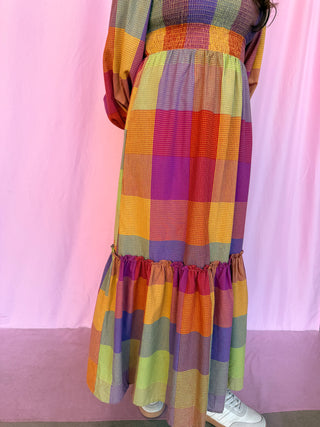 girl wearing plaid dress on a pink background