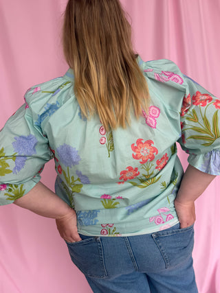 Person wearing a floral blouse with a pink background