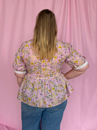 Person wearing a floral blouse with a pink background