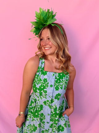 Woman wearing a green floral headpiece and a floral dress against a pink background