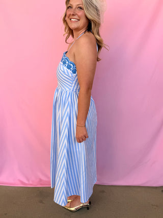Woman wearing a blue and white striped dress against a pink background