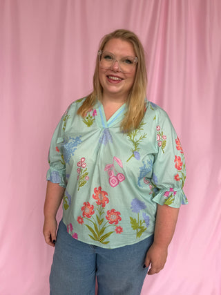 Woman wearing a floral blouse against a pink background