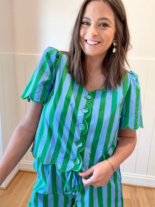 Woman wearing a green and blue striped dress with ruffled details.