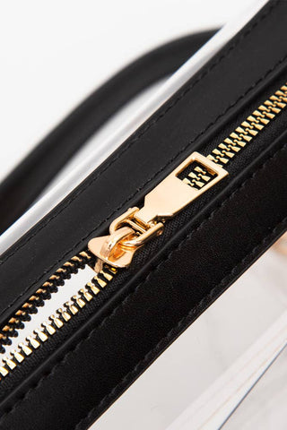 Close-up of a black strap with a gold zipper pull on a white background