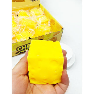 Yellow cube-shaped stress reliever held in a hand with a box of similar cubes in the background.