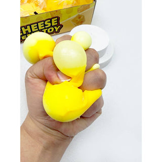 Hand holding a yellow stress ball with a box labeled 'Cheese Ball Toy' in the background.