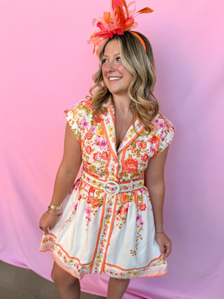 Woman wearing a floral dress and colorful headpiece against a pink background