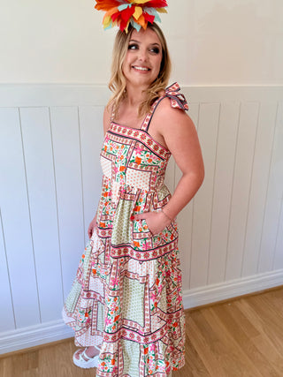 Woman wearing a colorful patterned dress with a white wall background