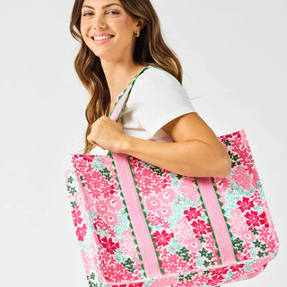 Woman holding a floral tote bag against a white background