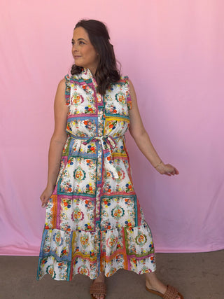 Woman wearing a colorful patchwork dress against a pink background
