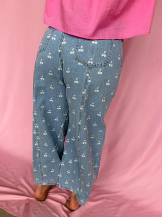 Person wearing blue jeans with white patterns on a pink background