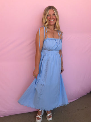 Woman wearing a light blue dress against a pink background