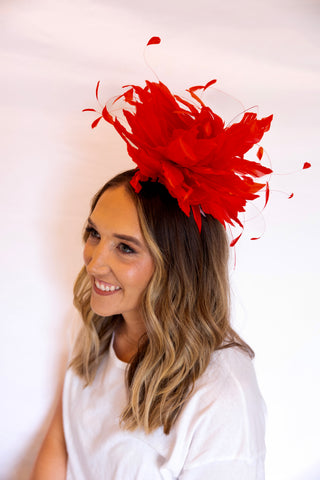Woman wearing a red feathered headpiece against a white background