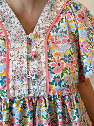 Colorful floral dress with pink trim on a neutral background