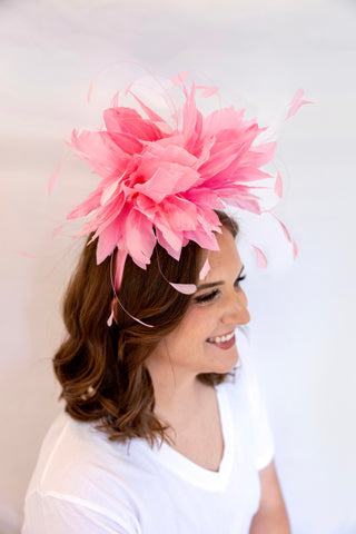 Woman wearing a large pink feathered headpiece against a white background