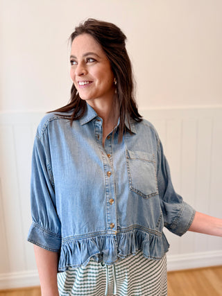 Woman wearing a denim shirt with a plain background