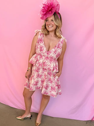 Woman wearing a pink floral dress and matching hat against a pink background