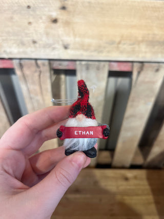 Small figurine with a red bandana labeled 'Ethan' held by a hand against a wooden background