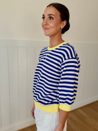 Woman wearing a blue and white striped sweater with yellow accents indoors.