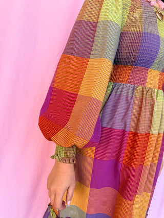 girl wearing plaid dress on a pink background