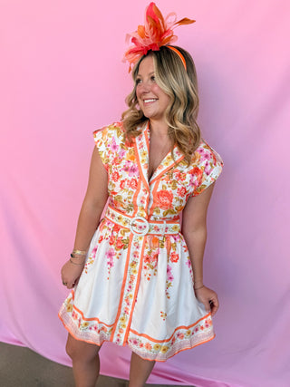 Woman wearing a floral dress and headpiece against a pink background