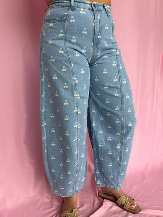 Light blue jeans with white patterns worn by a person on a pink background