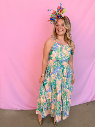 Woman wearing a colorful floral dress and headpiece against a pink background