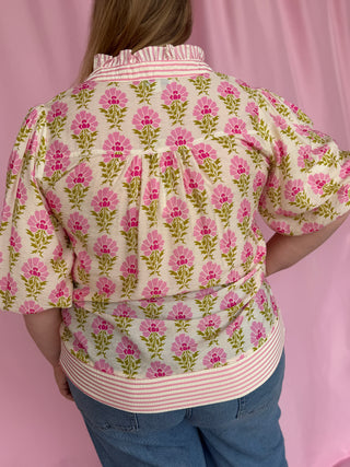 Person wearing a floral patterned shirt with a pink background