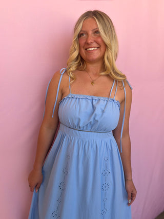 Woman wearing a light blue dress against a pink background