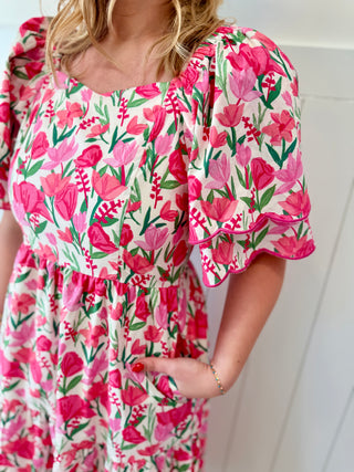 Woman wearing a pink floral dress with ruffled sleeves against a white background