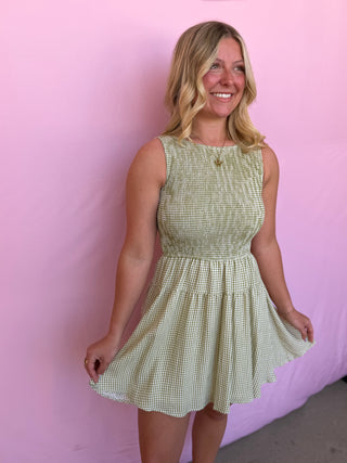 Woman wearing a green checkered dress against a pink background