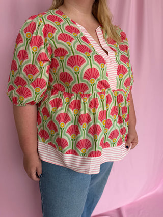 Person wearing a floral patterned blouse with a pink background