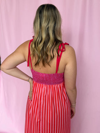 Woman wearing a red and white striped dress with a pink background