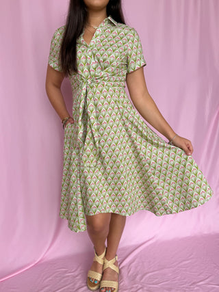 Woman wearing a green patterned dress on a pink background