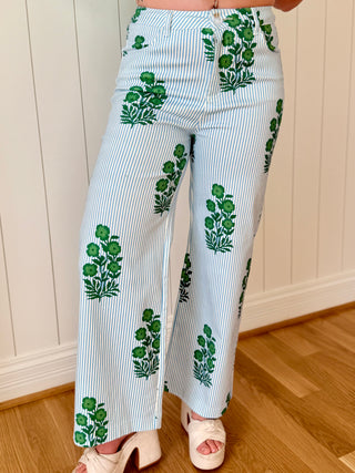 White pants with green floral patterns worn by a person indoors.