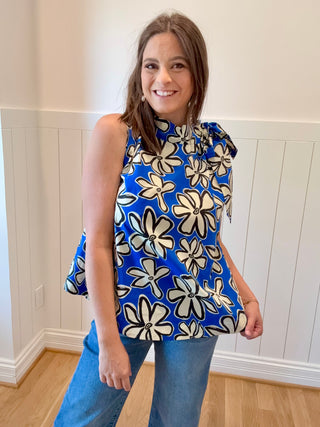 Woman wearing a blue floral top and jeans indoors.