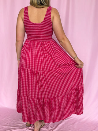 Person wearing a red and white checkered dress against a pink background