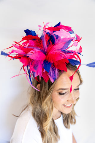 Woman wearing a colorful feathered headpiece against a white background
