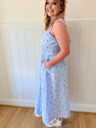 Woman wearing a blue checkered dress with a white wall background