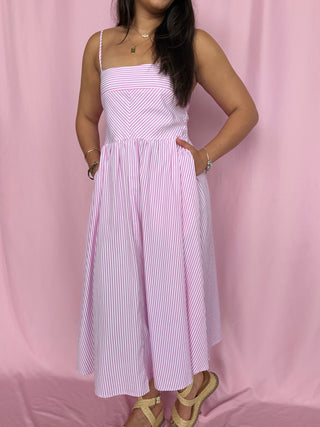 Woman wearing a pink and white striped dress against a pink background