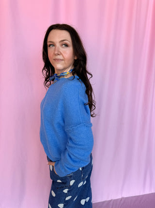 girl wearing blue sweater on a pink background