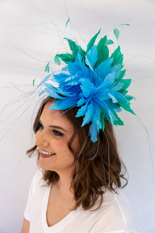 Woman wearing a blue feathered headpiece against a white background