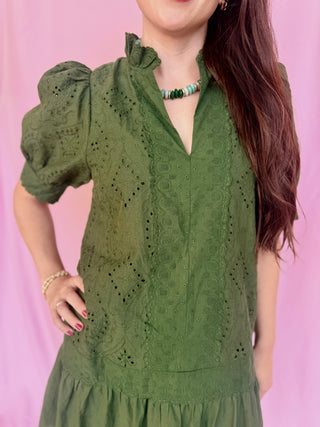 woman wearing a green dress on a pink background