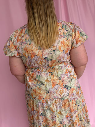 Person wearing a floral dress against a pink background